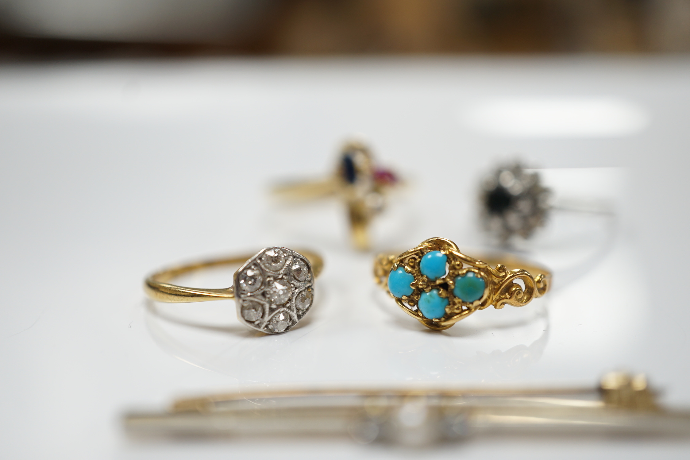 Three assorted 18ct and gem set rings, including 1920's diamond cluster, size K/L, one other early 20th century yellow metal and turquoise cluster set ring and a 15ct, diamond and seed pearl set three stone bar brooch.